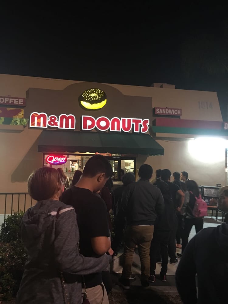 Customers lined up outside M & M Donuts at night